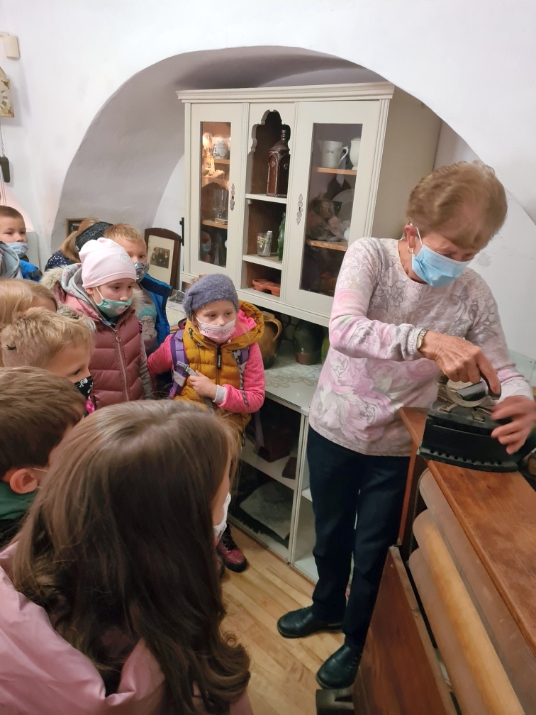 Frau Haneschová erklärt den Kindern ein altes Bügeleisen. 