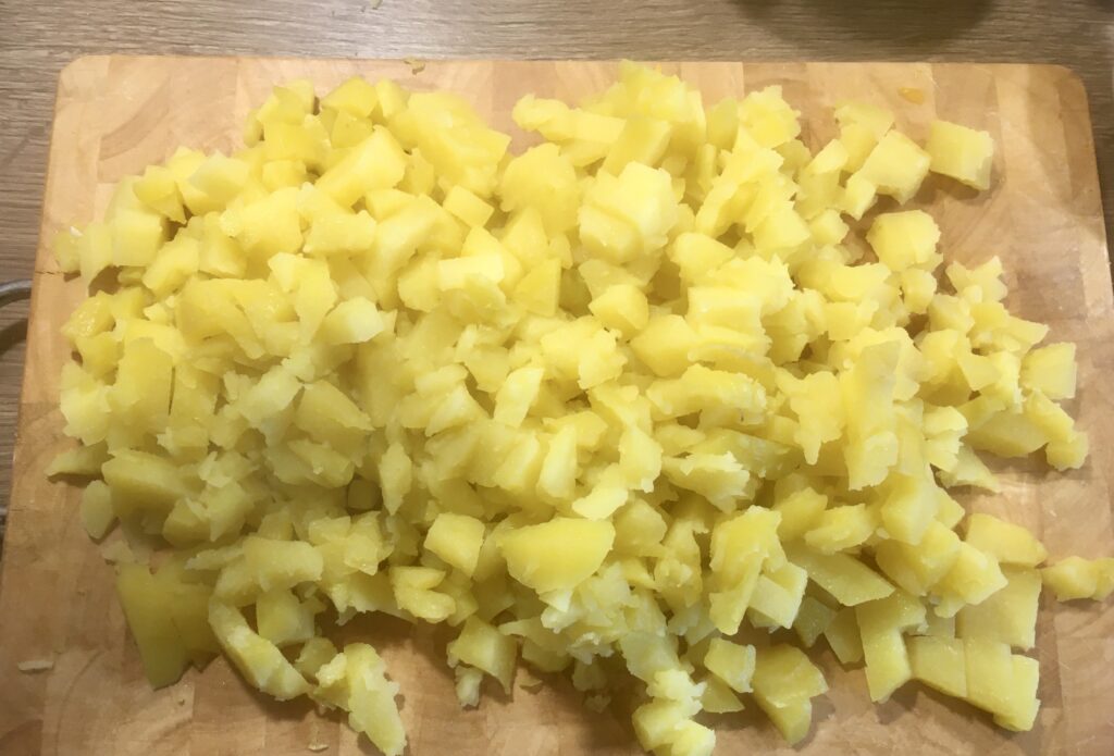 1. Die Pellkartoffeln (festkochende Kartoffeln), nachdem sie zuvor ca. 20 bis 30 Minuten gekocht und abgekühlt sind, schälen, in nicht zu kleine Würfel schneiden und leicht salzen.