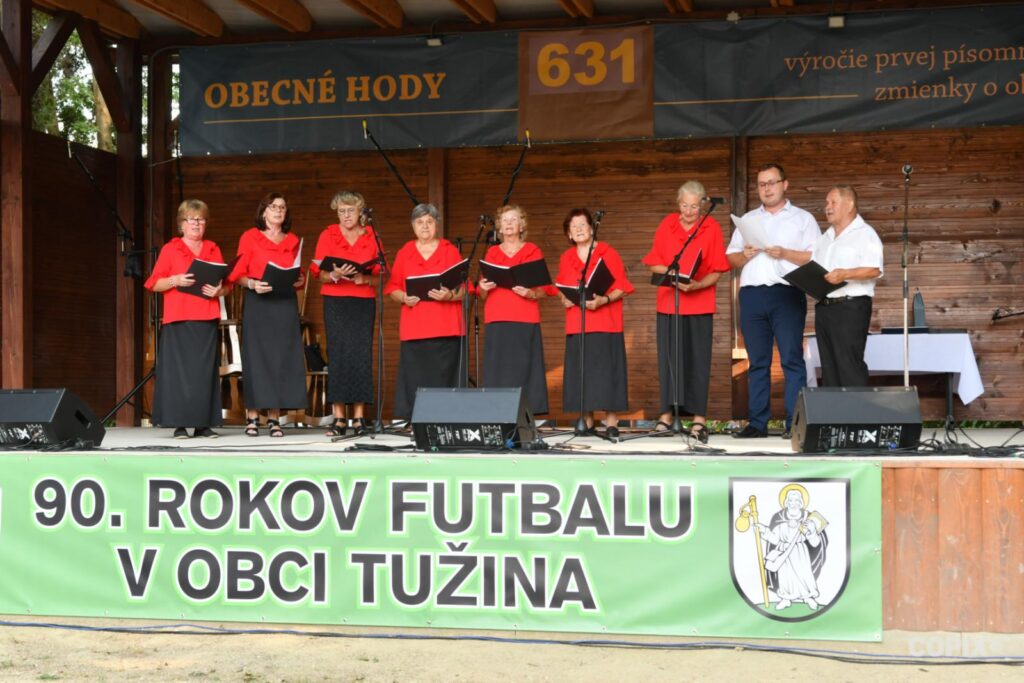 Ein Chor singt auf einer Bühne. Davor ein Plakat.